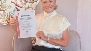 Beate Reinhart: sie zeigt ihr Zertifikat von TÜV AUSTRIA: Personenzertifizierung als Wertorientierter systemischer Coach und Berater, ISO/IEC 17024