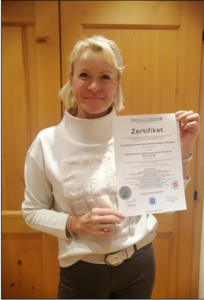 Beate Reinhart präsentiert stolz ihr Zertifikat als Wertorientierter systemischer Coach & Beraterin – ein Meilenstein in ihrer Coaching-Karriere.