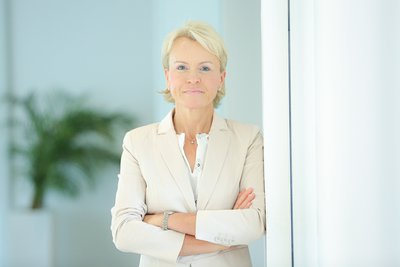 Beate Reinhart, Inhaberin von Kompetenz Mensch, mit verschränkten Armen vor einem hellen Hintergrund, symbolisiert ihre langjährige berufliche Erfahrung als Consultant, Mediatorin und Coach.